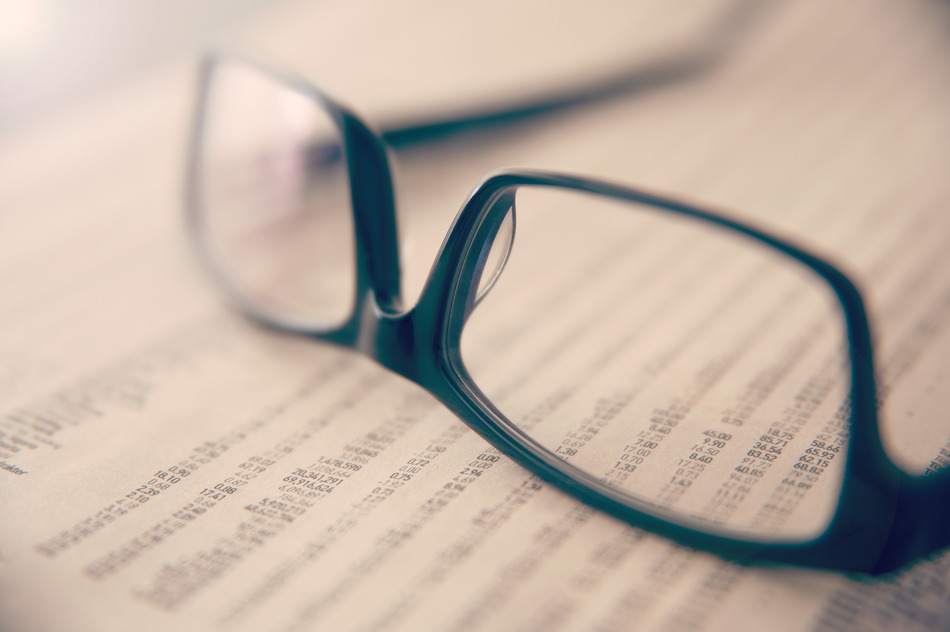 Eye glasses on newspaper showing stock exchange numbers